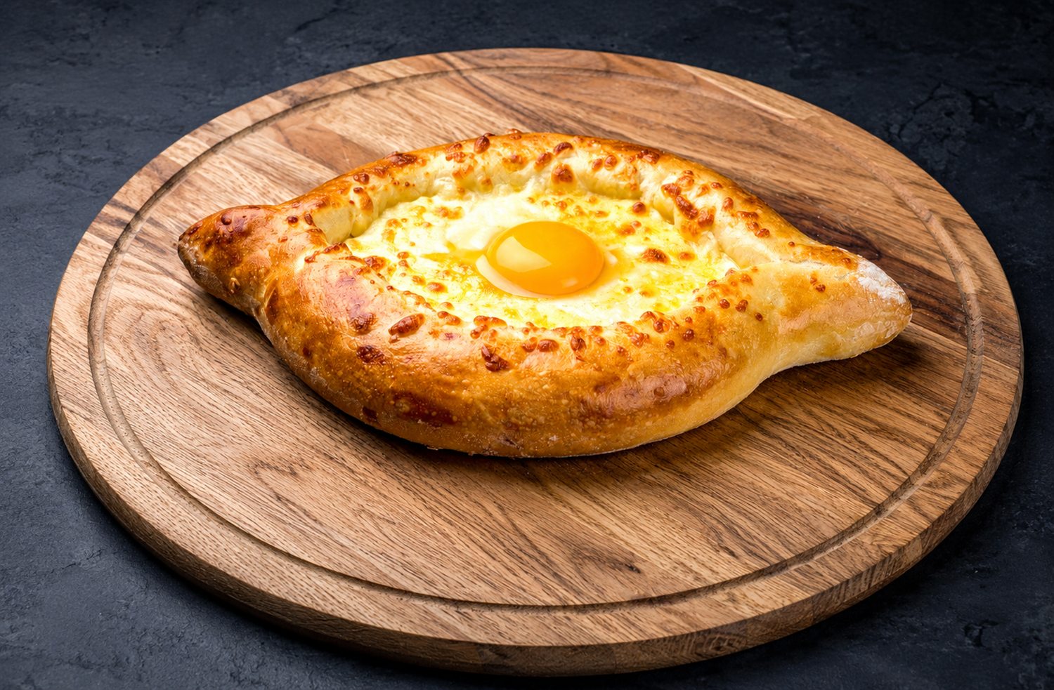 Acharuli khachapuri — boat-shaped Georgian cheese bread with an egg yolk and butter in the centre